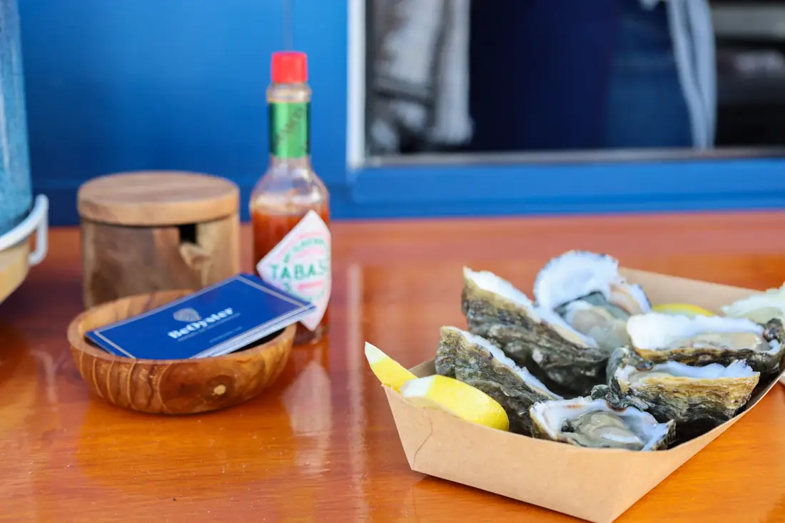 Ostras abertas numa caixa com limão, tabasco e cartão BeOyster